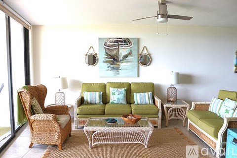 A living room with a green couch and a painting of a boat on the wall.