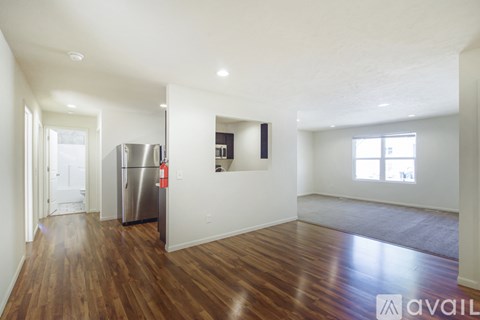 A kitchen with a stainless steel refrigerator and wooden floors.