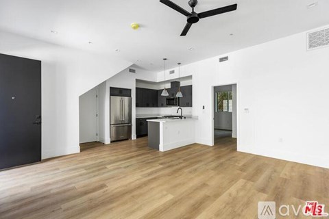 A spacious kitchen with a ceiling fan and wooden flooring.