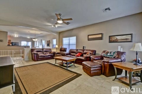 A living room with brown leather furniture and a ceiling fan.