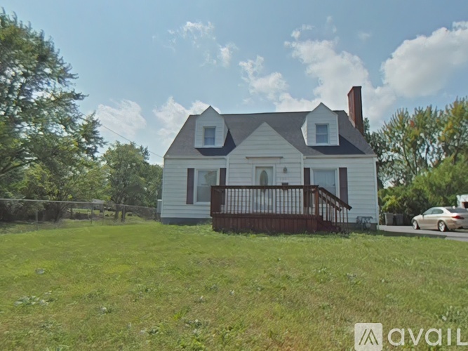A house with a white exterior and a brown deck is for sale.