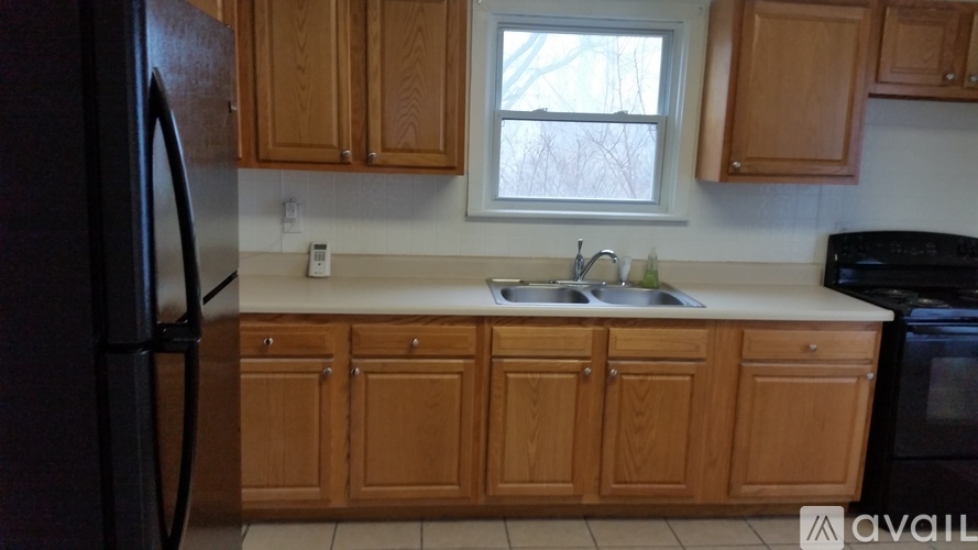 A kitchen with wooden cabinets and a black refrigerator.