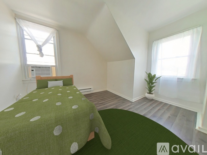 A bedroom with a bed covered in a green blanket with white polka dots.