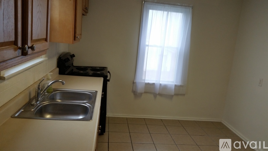 A kitchen with a sink and a window with white curtains.