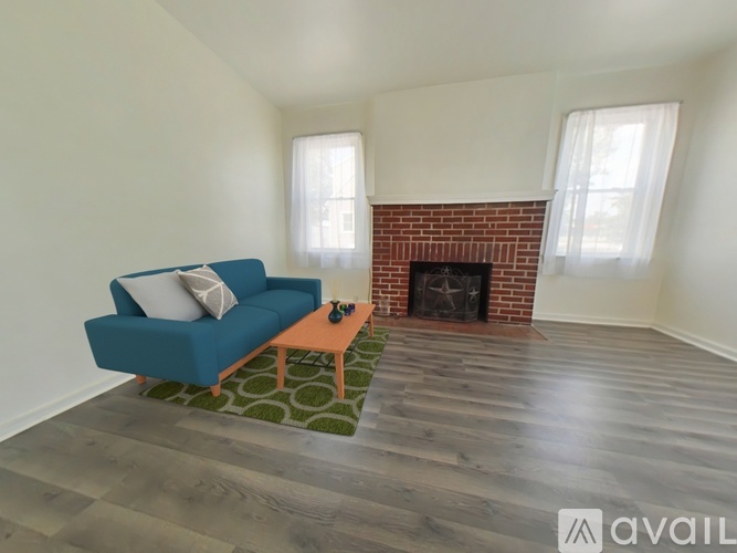 A blue couch sits in a living room with a brick fireplace.