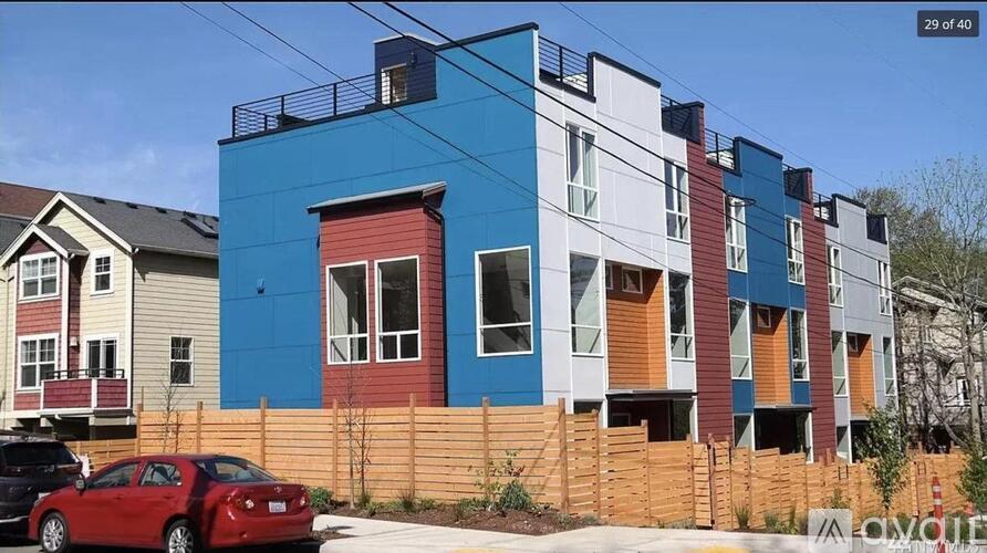 A red car is parked in front of a blue building.