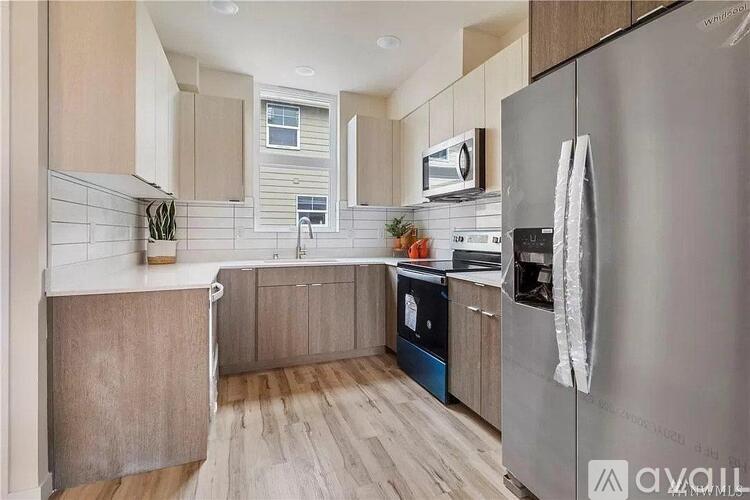 A modern kitchen with a stainless steel refrigerator and wooden flooring.