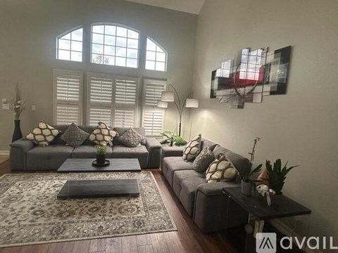 A living room with grey couches and a large window.