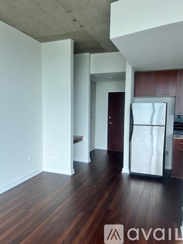 A kitchen with a refrigerator and wooden floors.