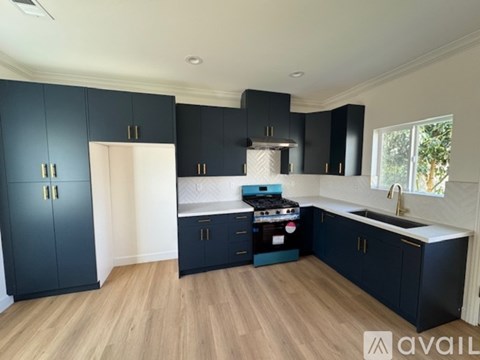 A kitchen with dark blue cabinets and a wooden floor.