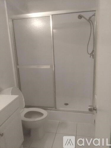 A white toilet in a small bathroom with a glass shower door.