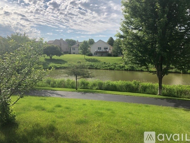 A house is situated by a pond with a tree in front of it.