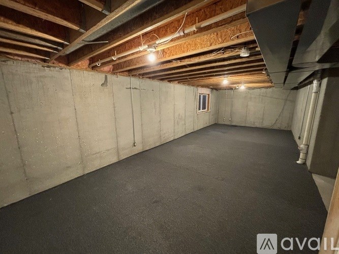 A spacious unfinished basement with concrete walls and ceiling, and a window.