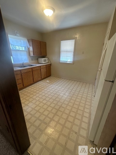 A kitchen with a white tile floor and a white fridge.