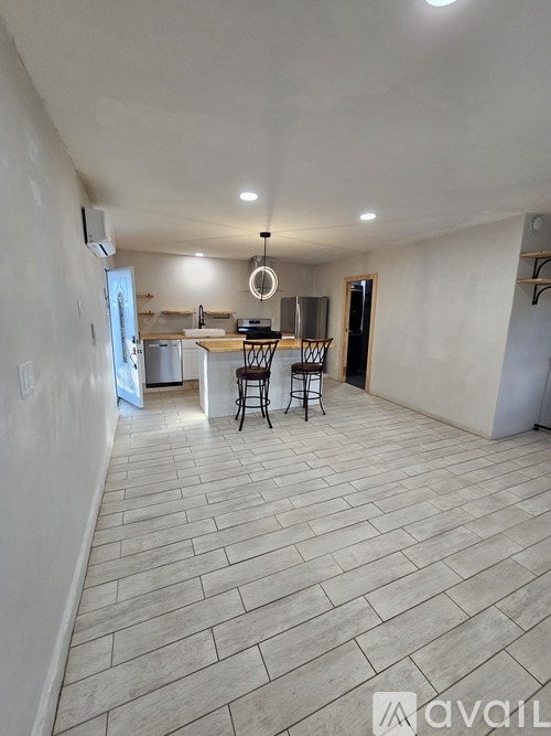 A spacious room with a kitchen area and a dining table.