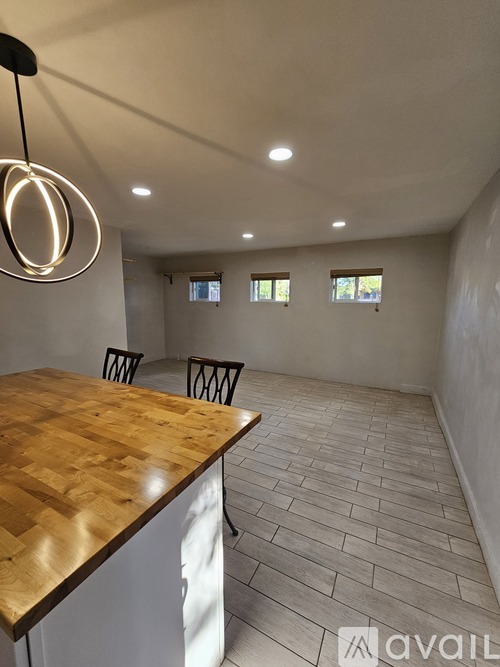 A room with a wooden table and chairs and a hanging light fixture.