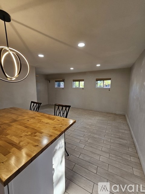 A room with a wooden table and chairs and a hanging light fixture.