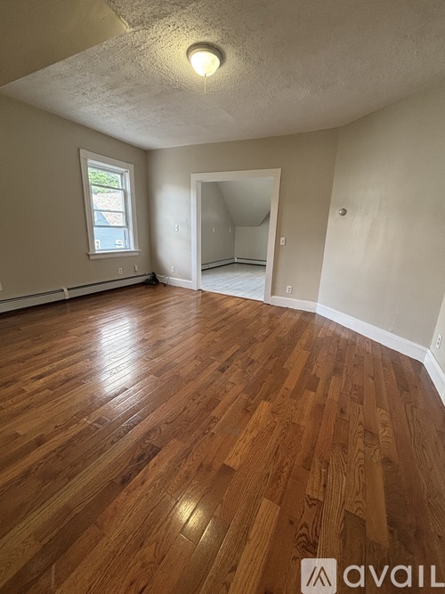 A room with wooden flooring and a window.