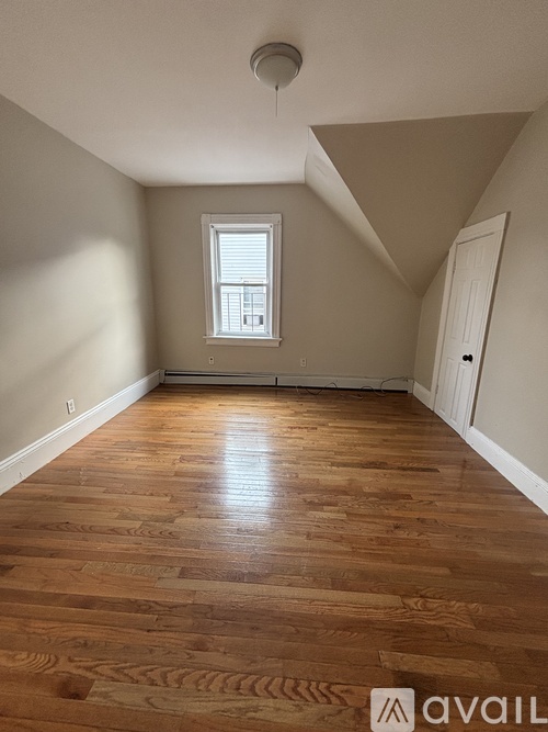 A room with wooden flooring and a window.