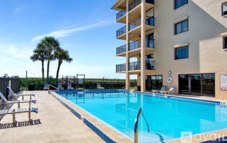 A pool in front of a building with a palm tree in the background.