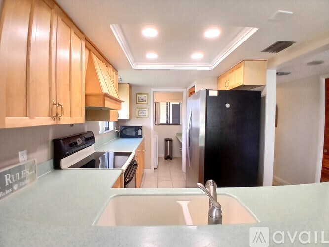 A kitchen with wooden cabinets and a black refrigerator.