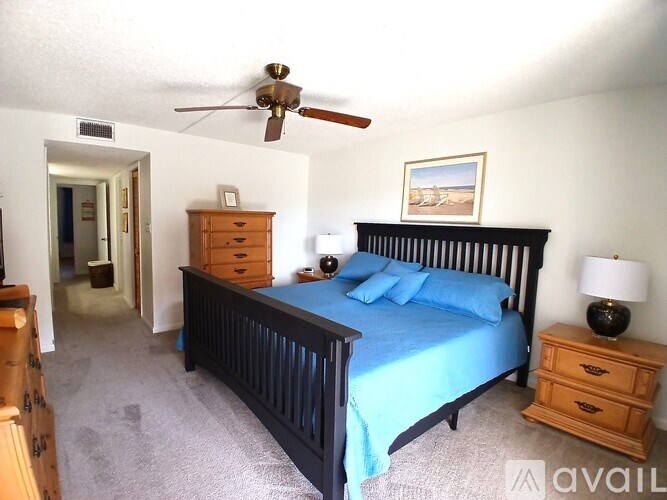 A bedroom with a bed, dresser, and ceiling fan.
