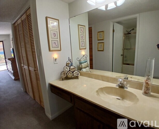 A bathroom with a sink, mirror, and a wall with pictures.