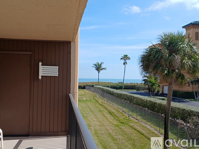 A balcony with a view of the ocean and palm trees.