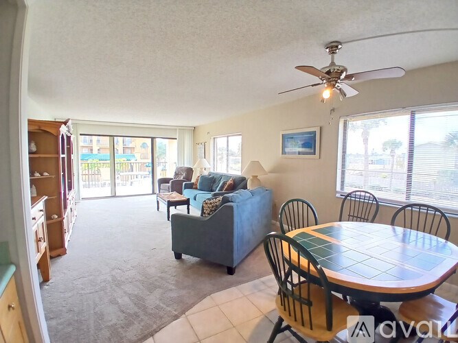 A living room with a grey couch, a table with four chairs, and a ceiling fan.