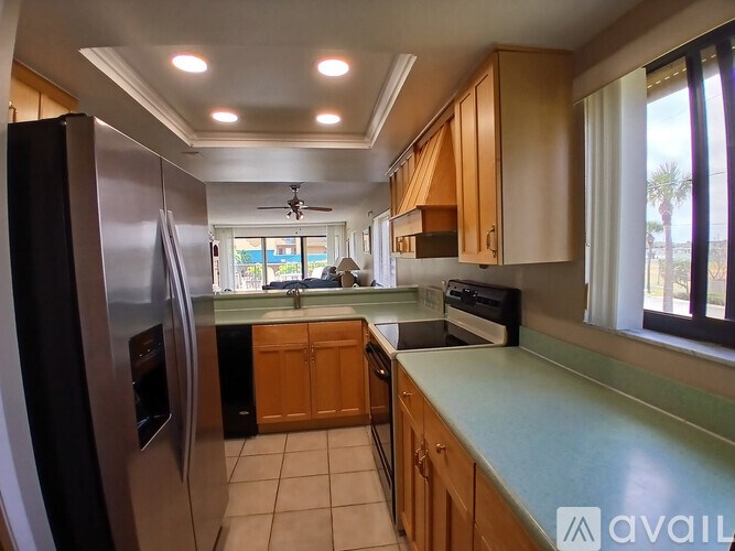 A kitchen with a refrigerator, sink, and cabinets.