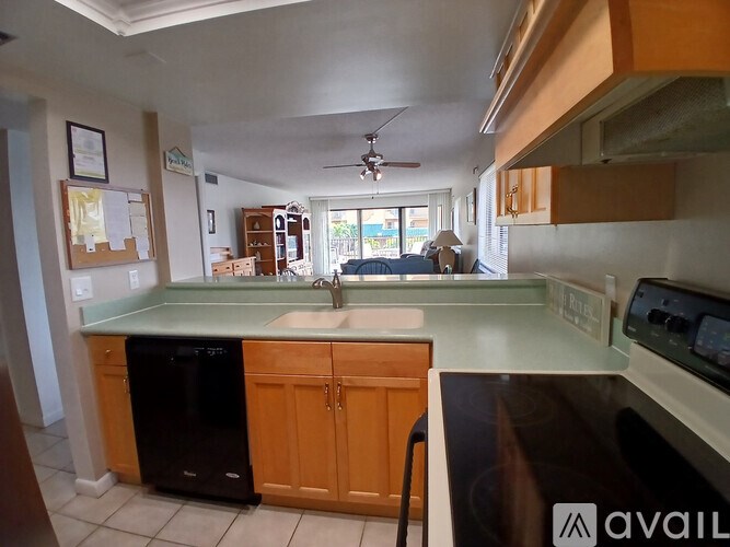 A kitchen with a black dishwasher and wooden cabinets.