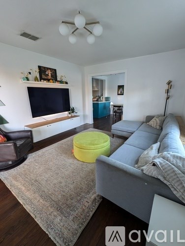 A living room with a grey couch and a yellow container on the floor.