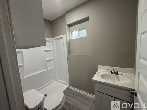 A bathroom with a toilet, sink, and a window.