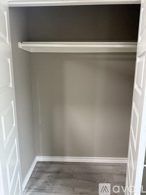 A white closet with a shelf and a grey floor.