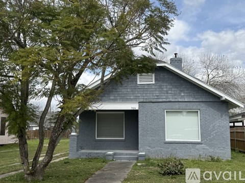 A house with a grey exterior and a tree in front.