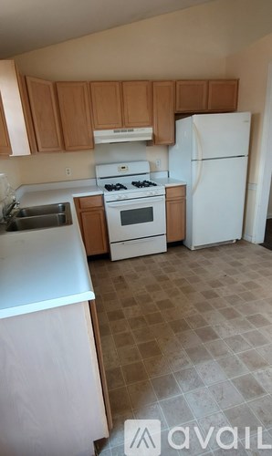 A kitchen with white appliances and wooden cabinets.
