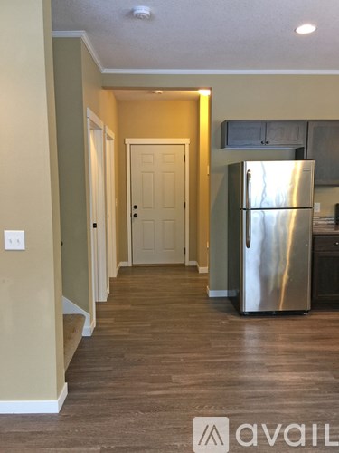 A kitchen with a stainless steel refrigerator and wooden flooring.