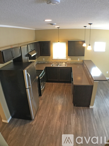 A kitchen with black appliances and wooden floors.