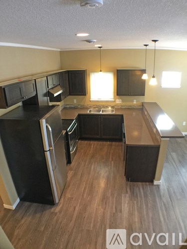 A kitchen with black appliances and wooden floors.