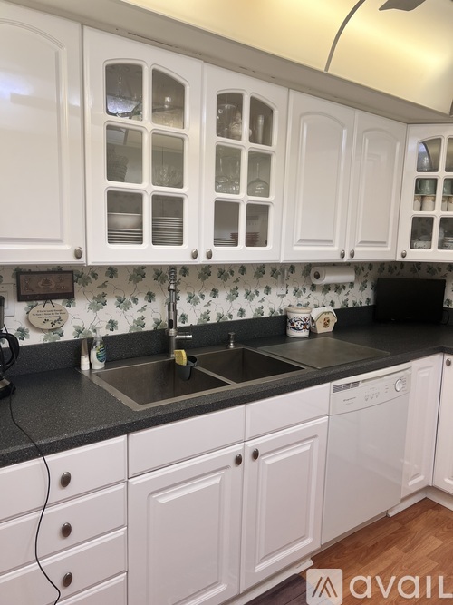 A kitchen with white cabinets and a black countertop.