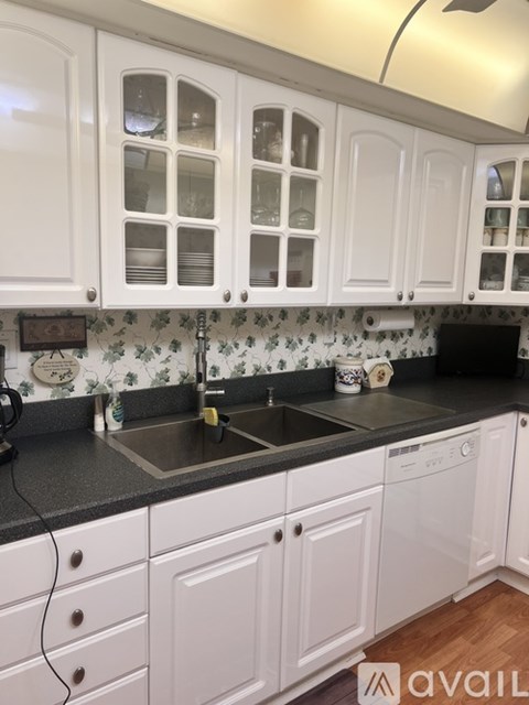 A kitchen with white cabinets and a black countertop.