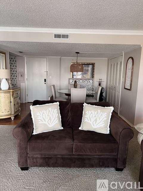 A brown couch with two white pillows is in the foreground of a living room.