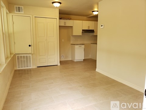 A kitchen area with a white dishwasher and cabinets.