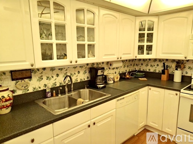 A kitchen with white cabinets and a black countertop.
