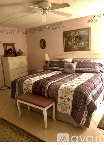 A bedroom with a bed, dresser, and ceiling fan.