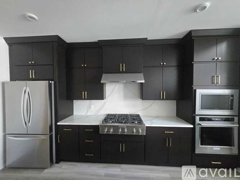 A modern kitchen with black cabinets and stainless steel appliances.