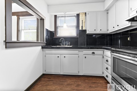 A kitchen with white cabinets and a black countertop.