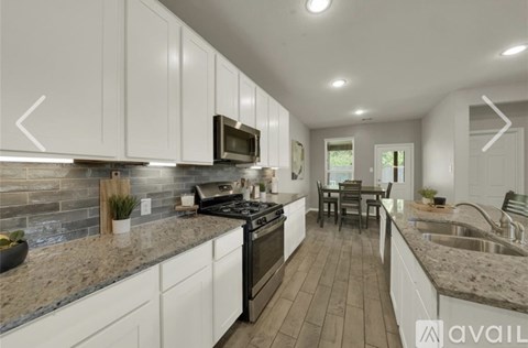 A modern kitchen with white cabinets and a granite countertop.
