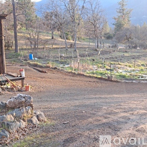 A dirt path leads through a field with a blue container and a wooden fence.