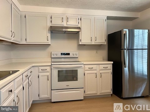A kitchen with white cabinets and appliances.